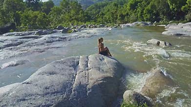 Drone Removes from Girl Silhouette on Boulder under Sunlight