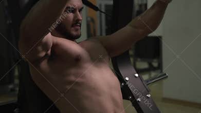 Athletic Sporty Man with Naked Torso Working Out on Exercising Machine.
