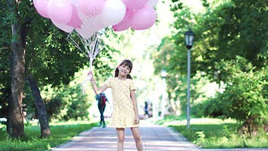 Portrait of little girl with balloons in her hands. carefree and happy child outdoors