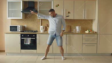 Handsome young funny man dancing in kitchen at home in the morning and have fun on holidays