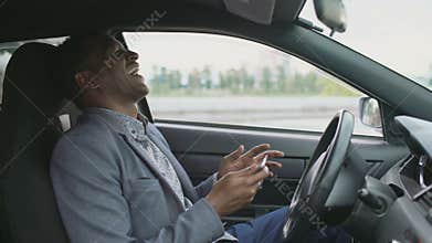 Happy african american businessman surfing social media on his tablet computer sitting inside his car