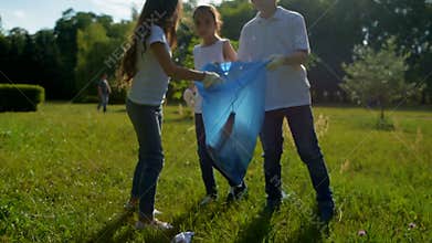 Little volunteers putting trash in garbage bag