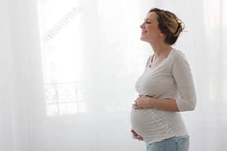 Pregnant happy woman touching belly and laughing