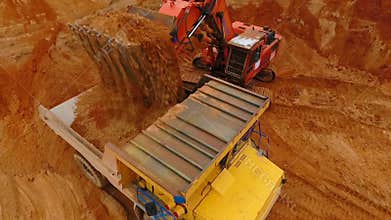 Mining excavator loading sand in dumper truck at sand quarry. Excavator bucket