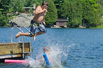 Boy dive bombing friend off dock into lake