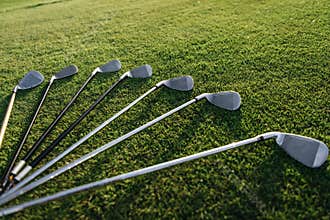 Set of shiny golf clubs arranged on grass