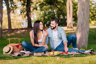 Couple resting on blanket while having picnic together