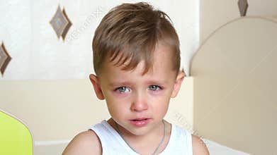 Little boy crying and sitting in his high chair.