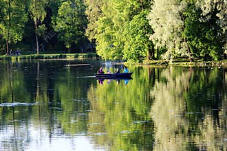 Evening Gatchina Park is lit by the summer sun.Family swims on a boat on the lake.