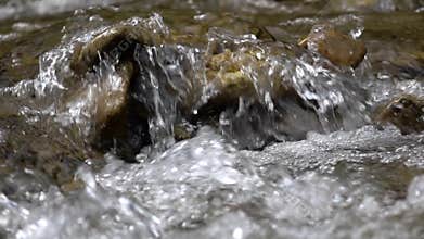 Closeups of water that overcomes rocky rapids in slow motion