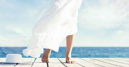 Beautiful and healthy feet of a young girl in white dress on a w
