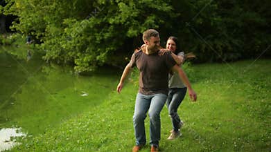 Handsome boyfriend carries girl on his back. Romantic couple is having fun outdoors during summer time at the city park