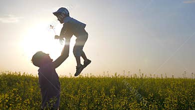 Parent fooling with son on meadow, happy dad with boy playing on background field, daddy and son play in park outdoors