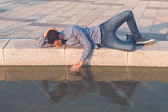 Young handsome man looking at himself in the water