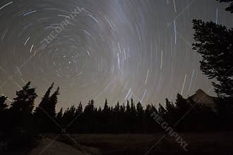 Starry night sky with circular star trails and blurred Milky Way