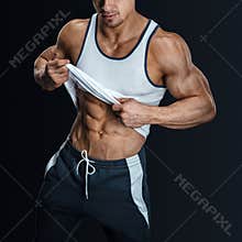 Athletic male model posing, pulling up tank top