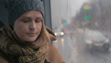 Young sad woman in the bus on a dull rainy day
