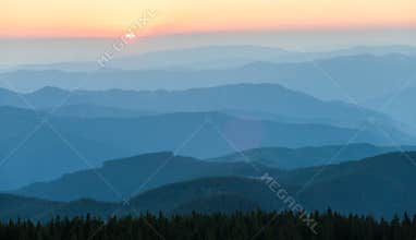 Distant mountain range and thin layer of clouds on the valleys