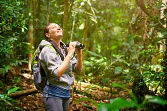Hiker watching through binoculars wild birds in the jungle.
