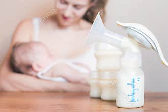 Manual breast pump and mother feeding a newborn baby