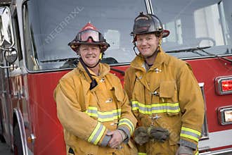 Portrait of two firefighters by a fire engine