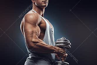 Young man with dumbbell prepare to flexing muscles over dark background