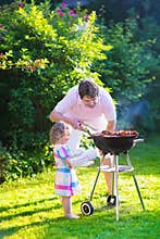 Father and daughter grilling meat
