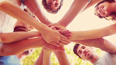 Happy friends stacking hands together in the park