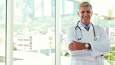 Happy doctor looking at camera with arms crossed