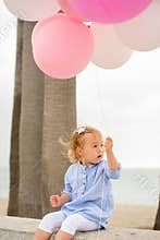 Cute little blond girl holding party balloons