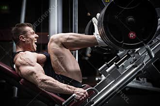 Man in gym training at leg press