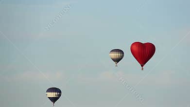 Balloon in shape of heart, three hot air balloons flying in the sky
