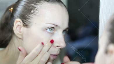 Woman squeezes pimples on his face looking