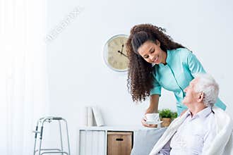 Female caregiver serving afternoon tea to patient