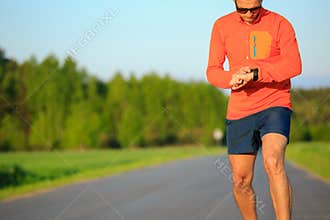 Runner training and checking stopwatch smart watch, cross country