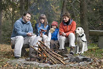 Happy family with dog near campfire