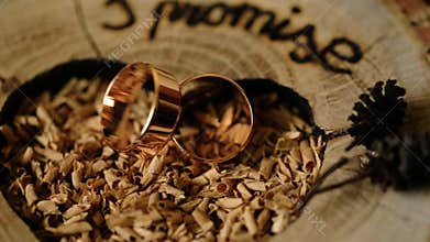 Gold wedding rings on a wooden background decorated for a marriage ceremony.