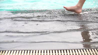 Slow motion shoot of feet walking by pool . Little child walking near swimming pool