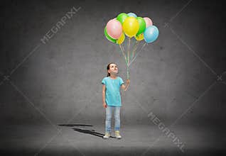 Girl looking up with bunch of helium balloons