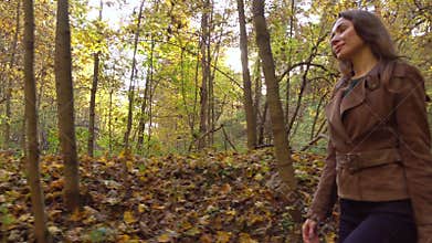 Pretty girl walking through autumn woods holding a picnic basket. Profile view, 4K steadicam video