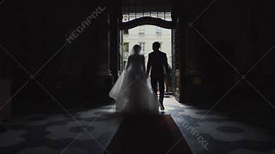 Wedding couple silhouettes coming out from church