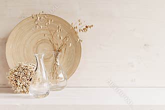 Soft home decor of glass vase with spikelets and wooden plate on white wood background.
