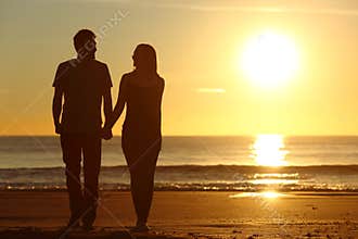 Couple silhouette walking together on the beach