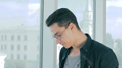 Professional photographer taking pictures with professional camera near panoramic window in modern office.