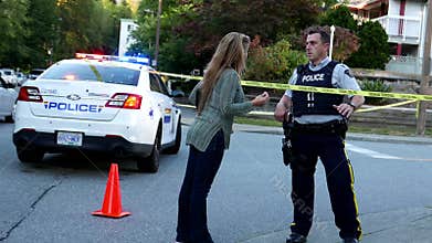 Woman asking fire situation to police between police caution line in residential neighborhood street blocking traffic