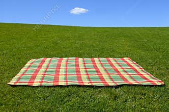 An empty picnic blanket on green grass
