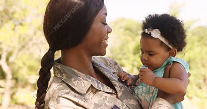 Soldier mother holding her daughter in a park