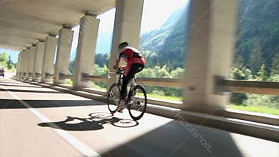 Competing cyclist shot from behind in underpass with pillars