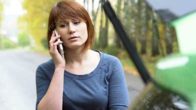 The woman making emergency call to recovery services with broken car. Warning triangle on country road