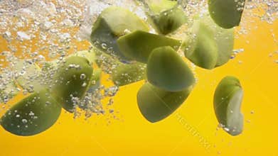 Sliced green apples falling underwater